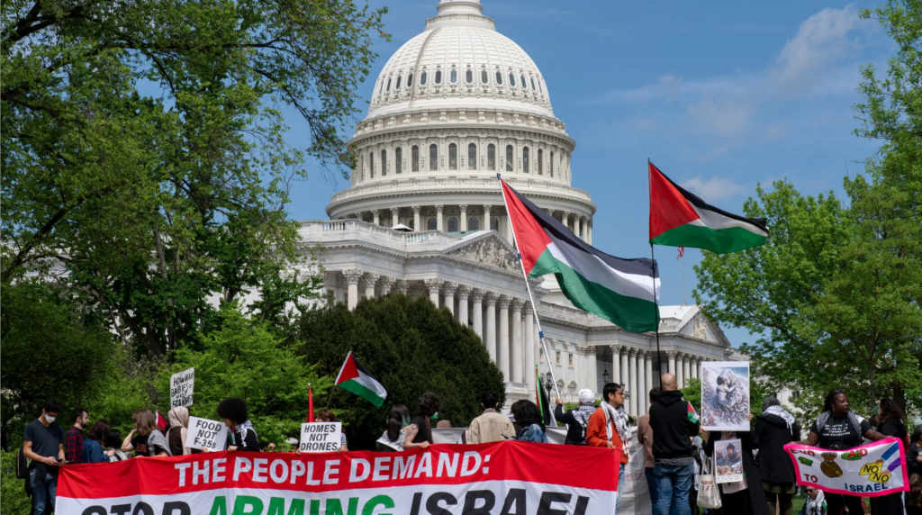 Protesters stand infant of the US Capital with Palestinian flags and a banner that reads "The People Demand: Stop Arming Israel"